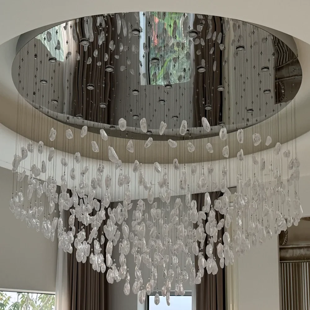 Grand lustre cascade à pampilles en verre suspendu sous un plafond miroir en double hauteur