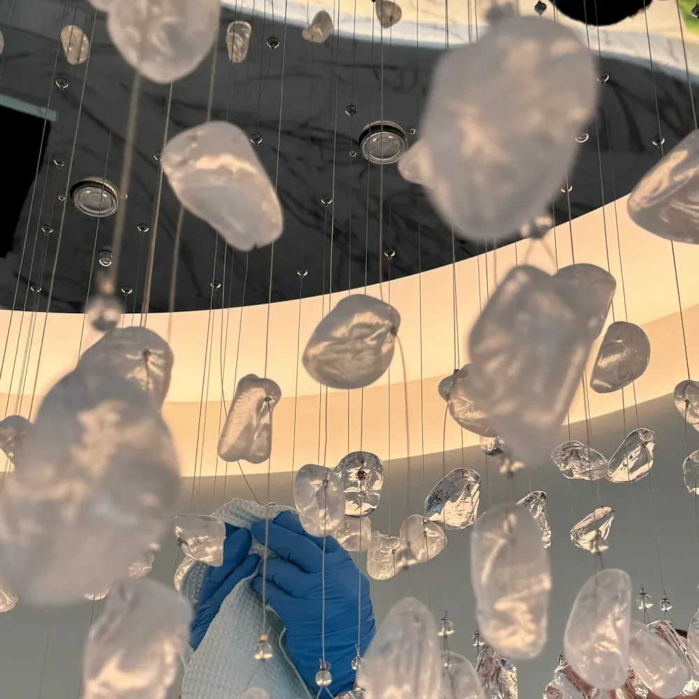 Nettoyage à la main des pampilles en verre d'un lustre avec gants et chiffon microfibre