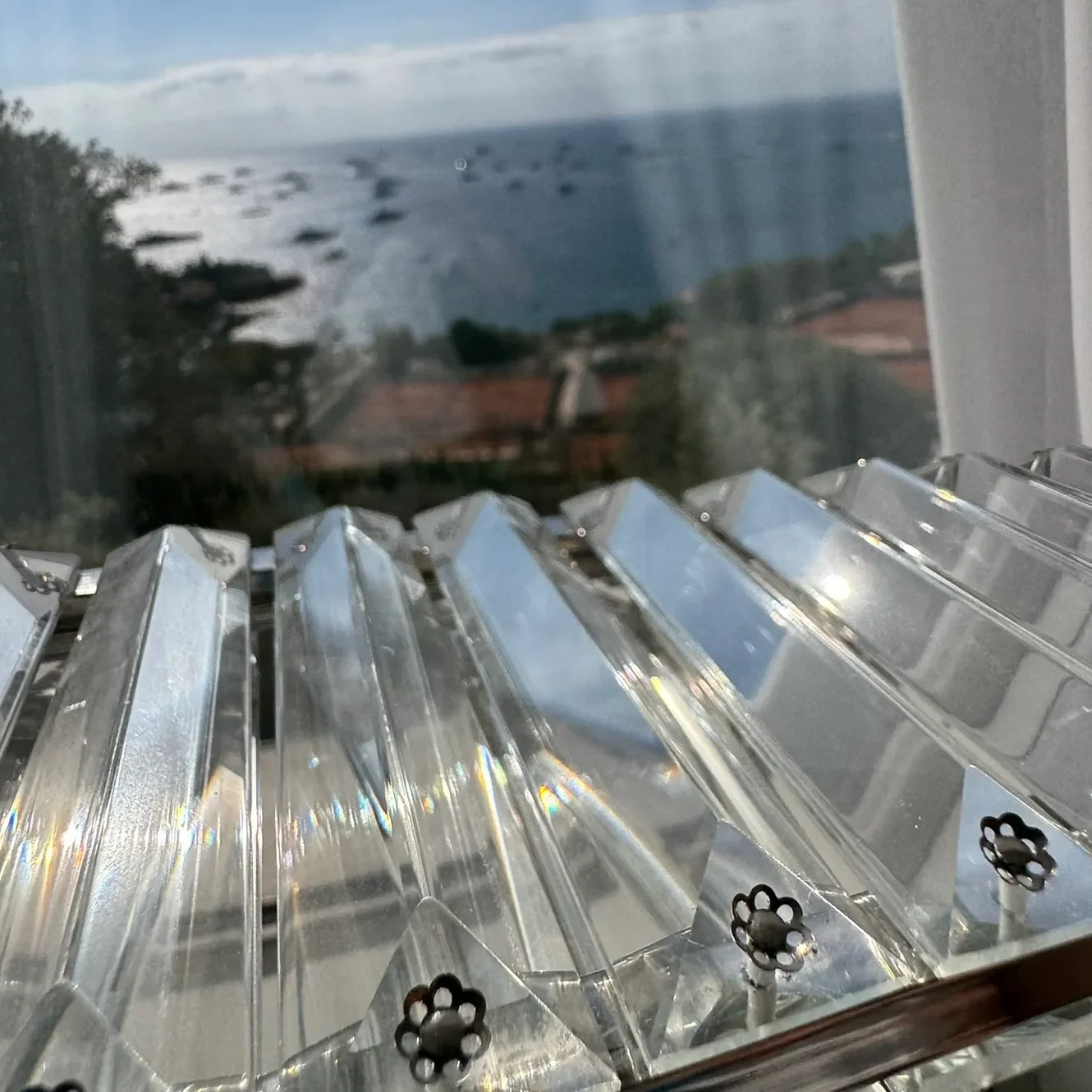 Pampilles en cristal d'un lustre nettoyé, avec vue sur la mer et Monaco en arrière-plan