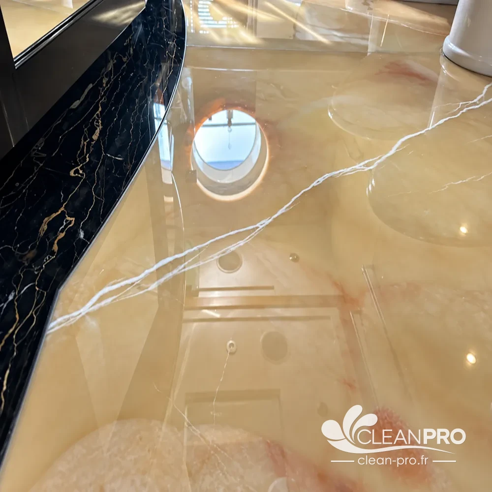 Sol en onyx miel et bordure en marbre noir veiné d'or polis, effet miroir, dans la salle de bain d'un yacht à Monaco