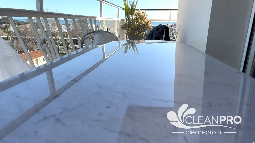 Plateau de table en marbre blanc poli et brillant sur une terrasse à Nice, avec reflets de la balustrade